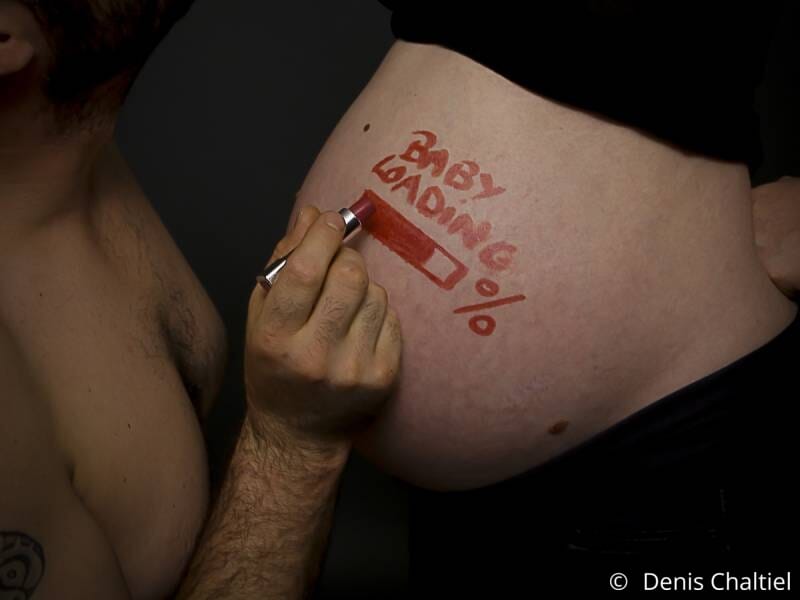 Une ventre de femme enceinte sur lequel un homme écrit